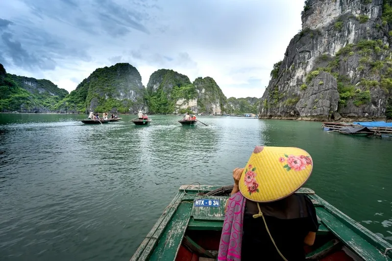 Traveller in a conical hat on a rowing boat in Halong Bay