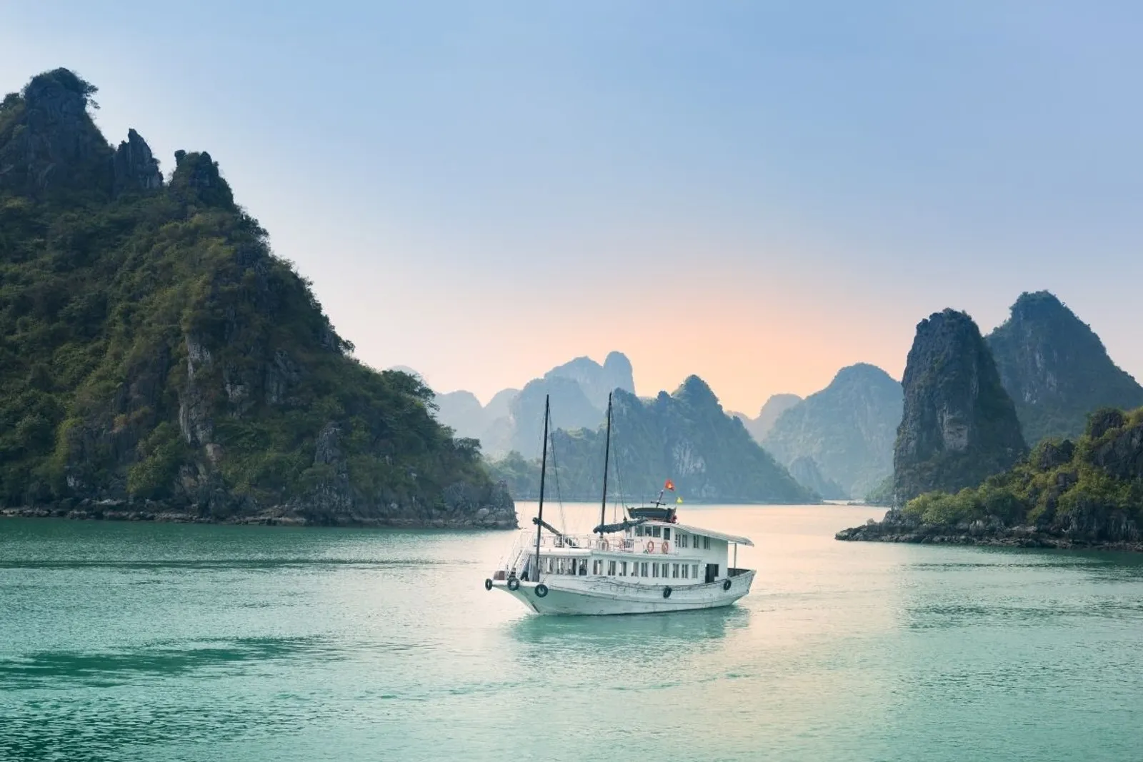 A boat sailing among limestone islands in Halong Bay