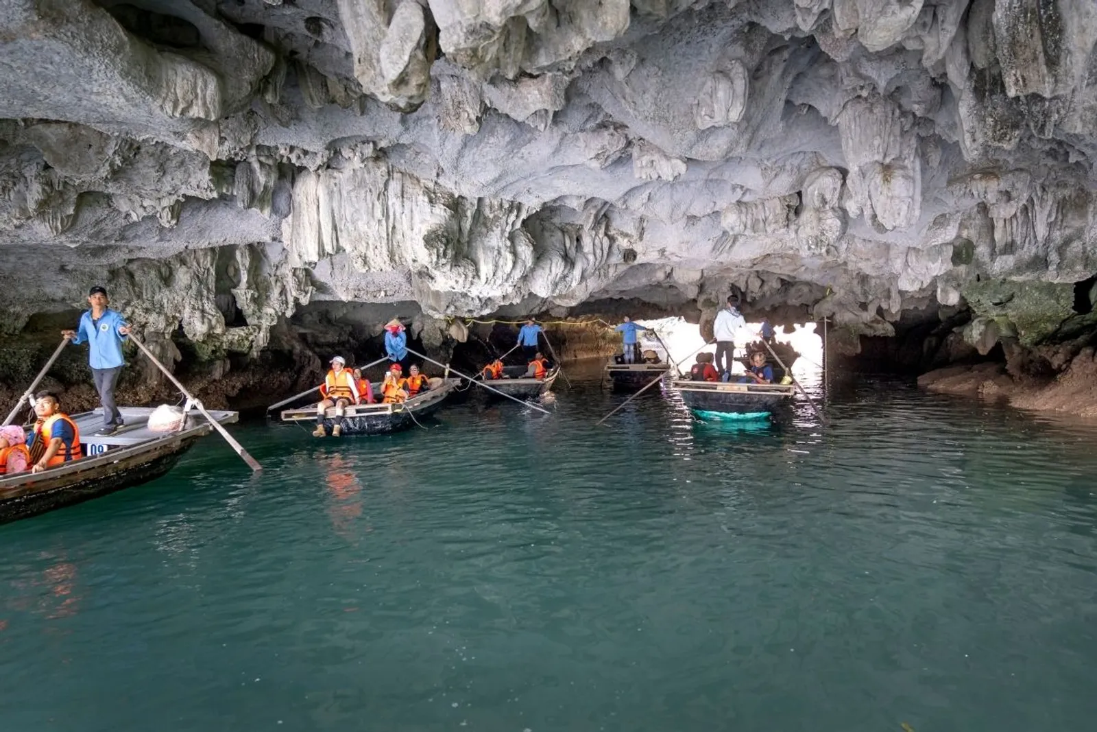 Sampans rowing through a cave arch in Halong Bay