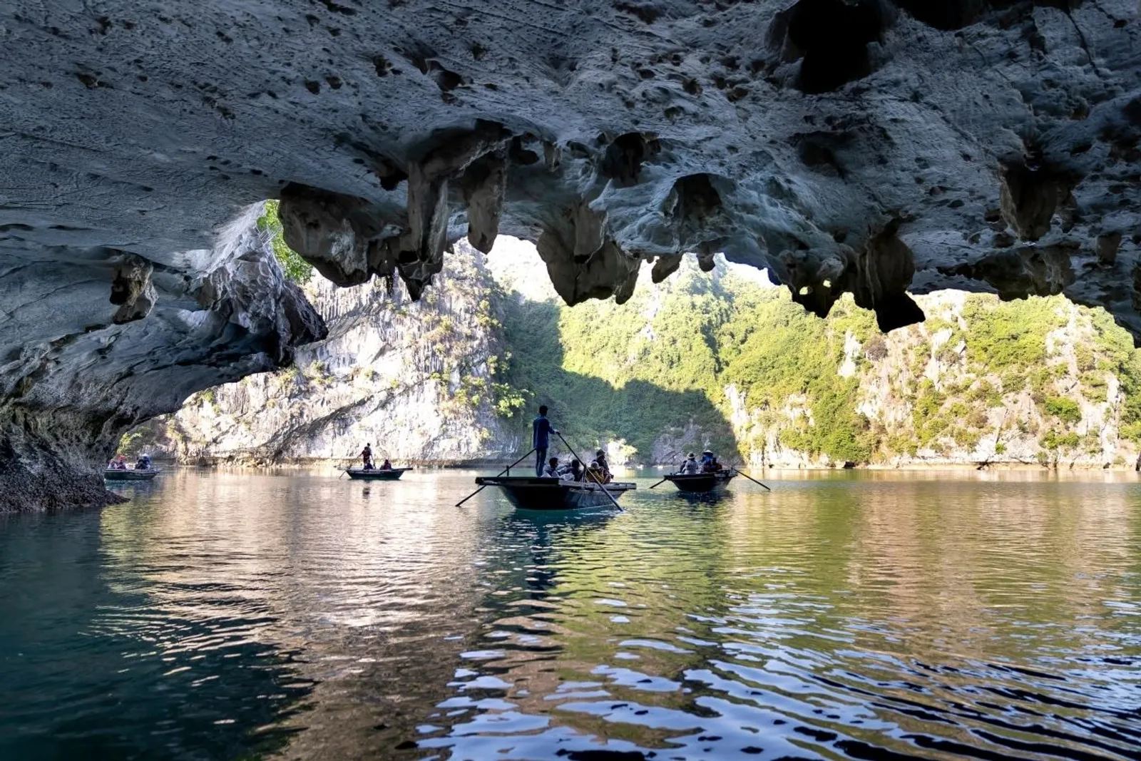Boats in a lagoon seen through a cave arch, Halong Bay